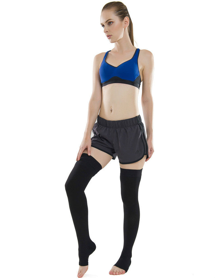 Woman standing wearing black thigh high compression stockings