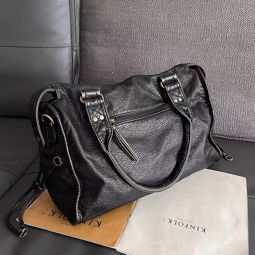 Women's black handbag resting on surface displaying sleek exterior and hardware