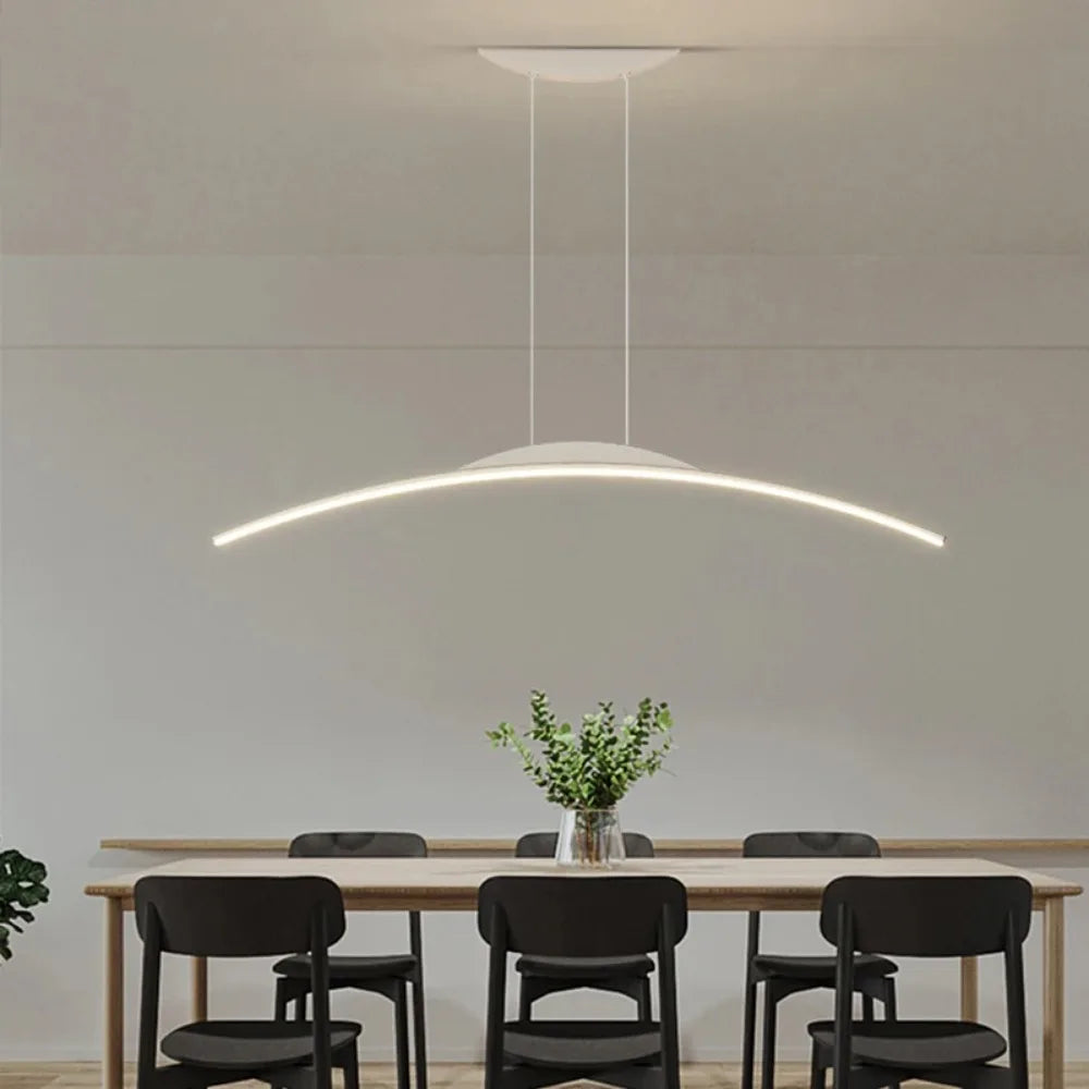 White modern LED pendant light suspended above a wooden dining table with chairs