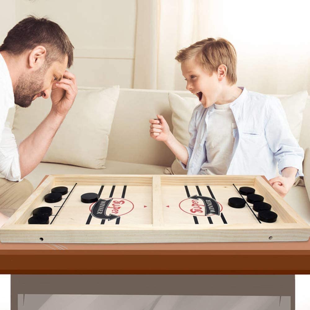 Father and son playing wooden table hockey game together in the living room