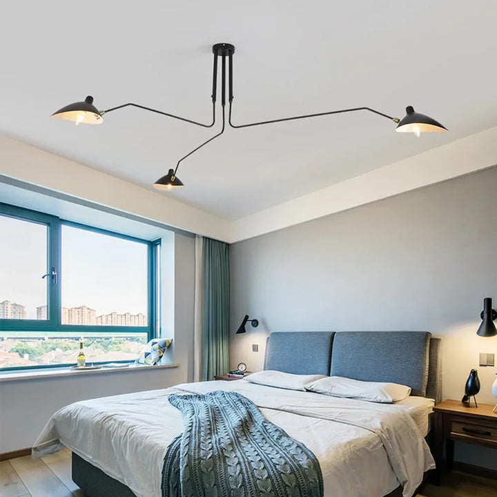 Black ceiling lamp with swivel arms illuminating a contemporary bedroom interior