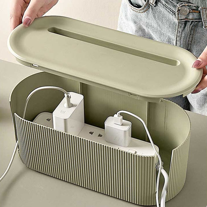 Hands opening the green cable organizer box with power strip inside