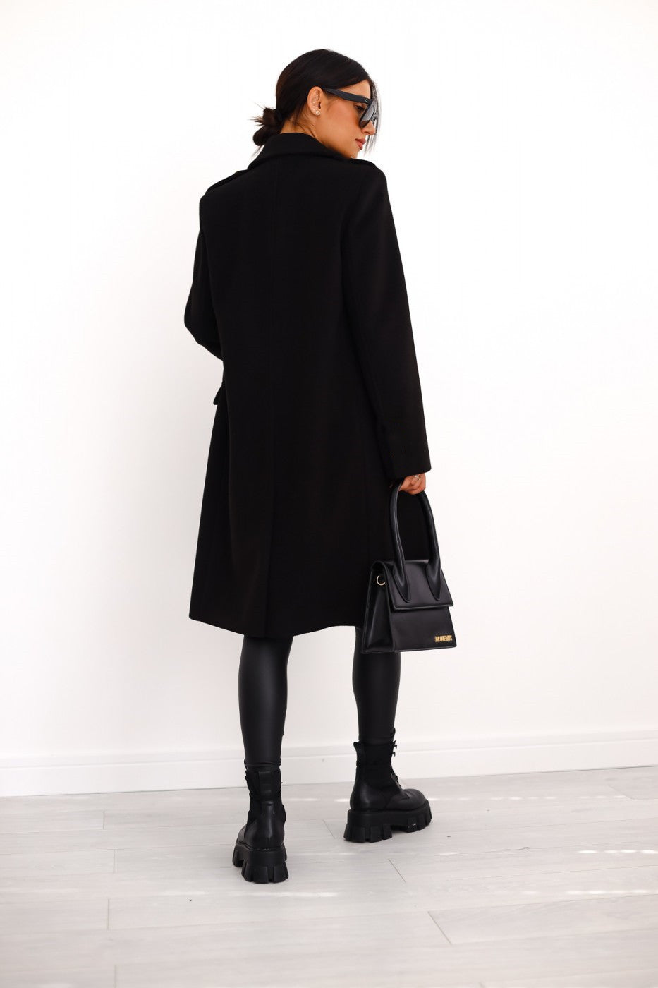 Back view of a woman wearing a black double-breasted long coat