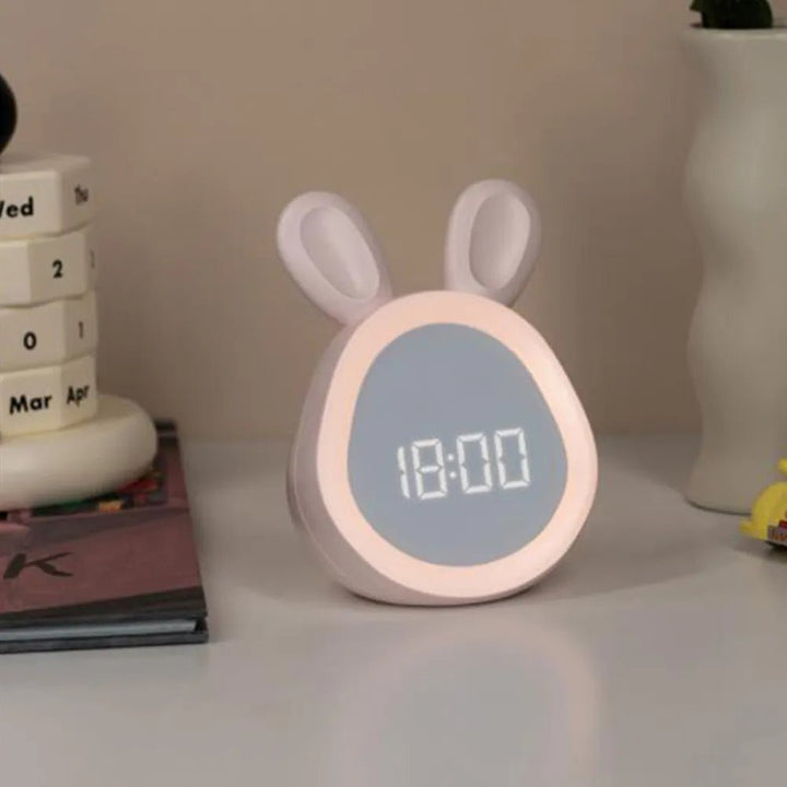 Pink children's bunny LED alarm clock on a bedside table in a kids room