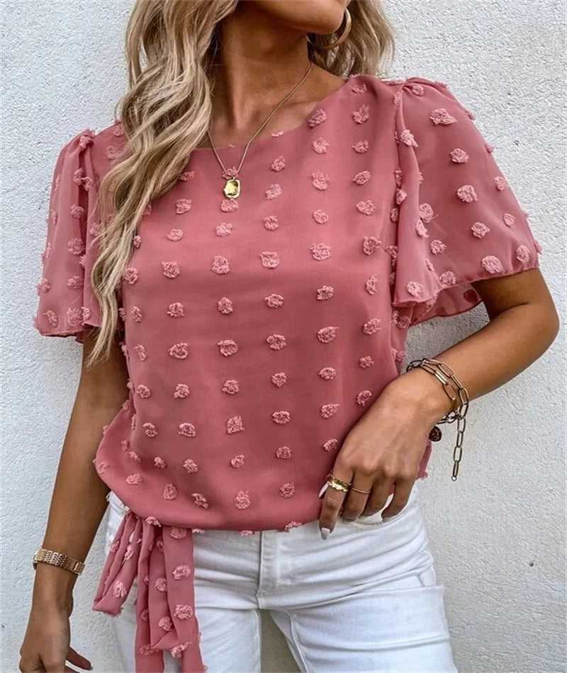 Woman wearing pink Beatriz blouse with 3D floral details and white jeans