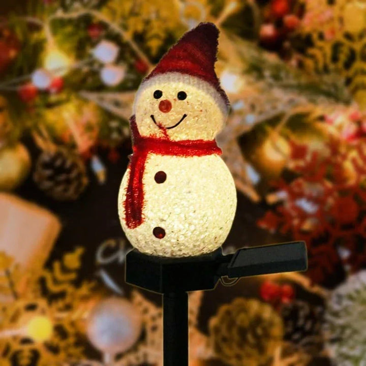 Close-up view of a glowing snowman decorative light with a red scarf and hat