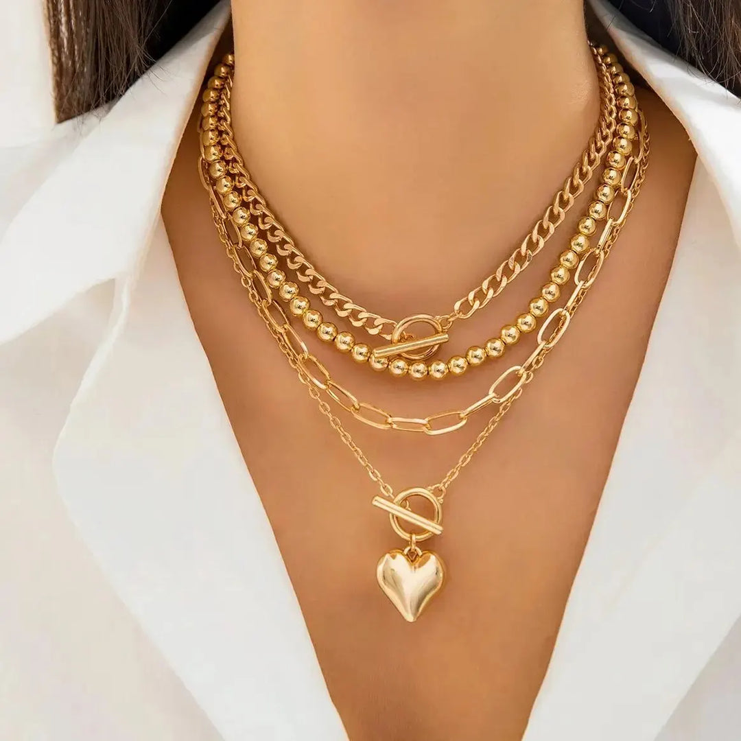 Model wearing a 4-piece layered gold necklace set with a heart pendant