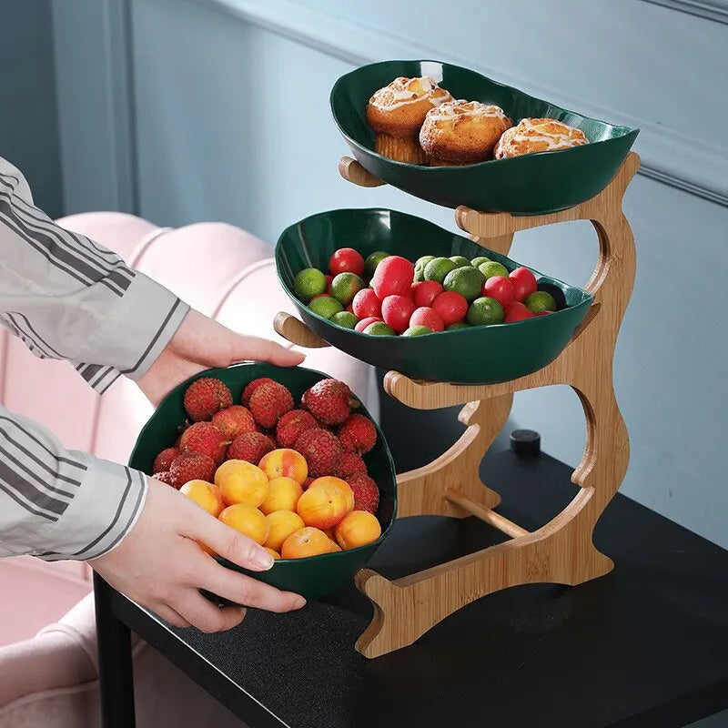 Green three-tier fruit bowl filled with fresh fruit and pastries on a table