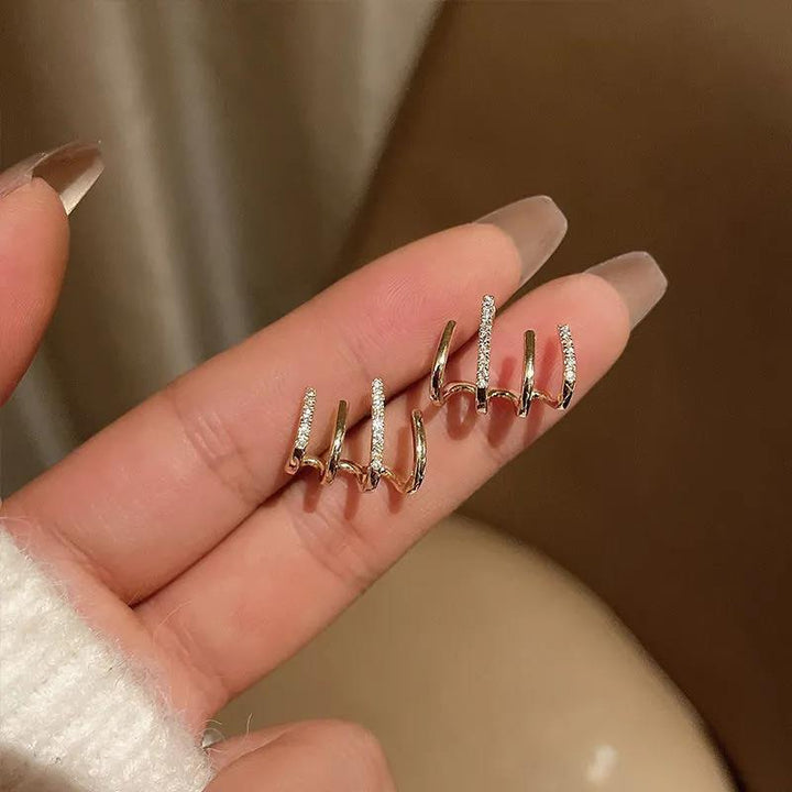 Gold claw earrings held on a hand showcasing their size and shape
