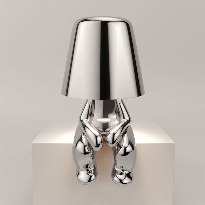 Gold modern wireless table lamp casting a warm glow on a wooden nightstand