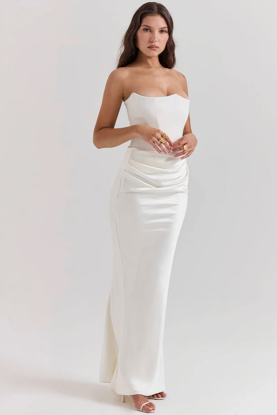 Three-quarter view of a woman posing in a stunning white strapless corset maxi dress