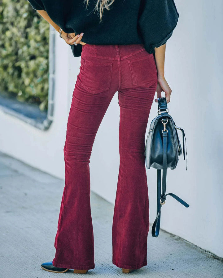 Back view of a woman wearing burgundy flared trousers and holding a handbag