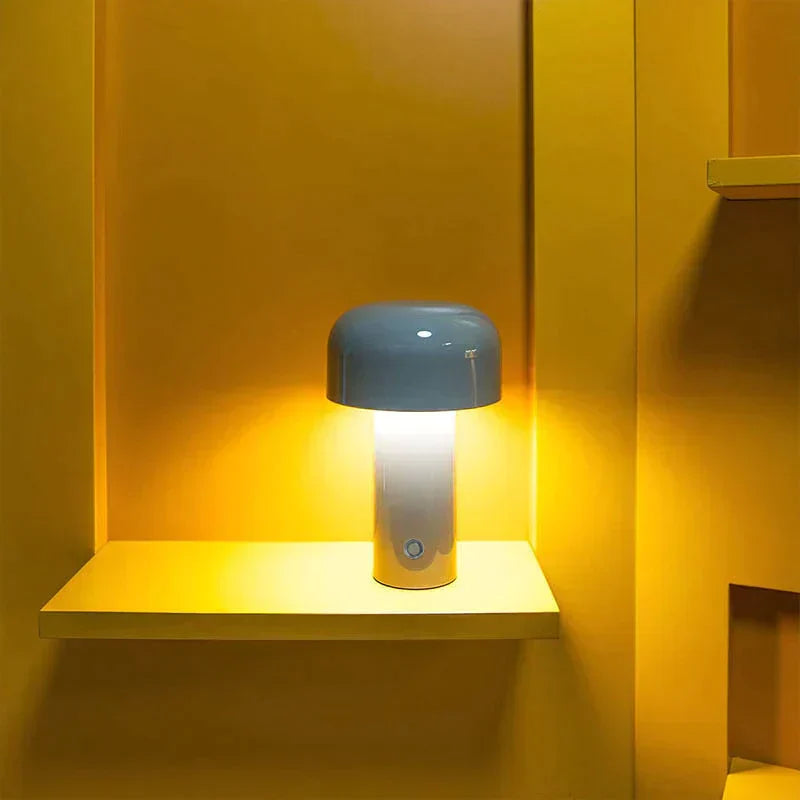 A blue wireless retro LED table lamp casting a warm glow against a yellow wall.