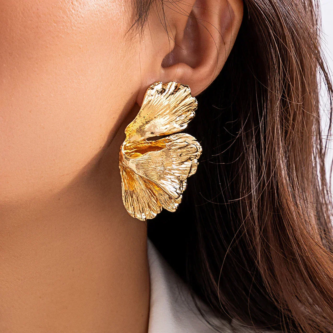 Close-up of woman wearing elegant gold petal drop earrings