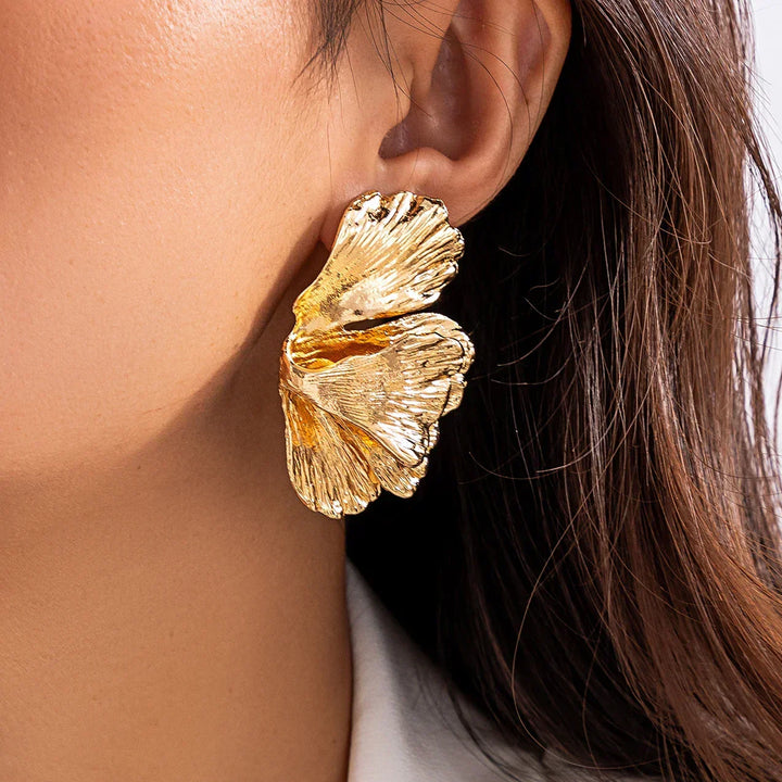 Close-up of woman wearing elegant gold petal drop earrings