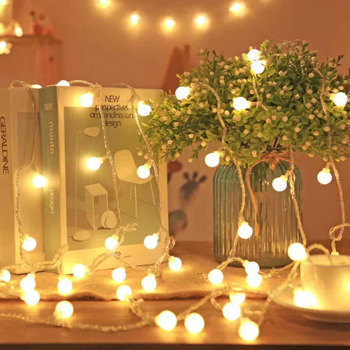 Warm white fairy string lights draped around books and a vase