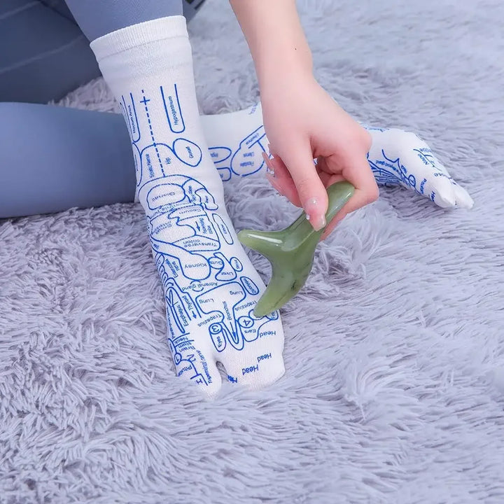 Demonstrating reflexology socks with a jade massage tool on a foot