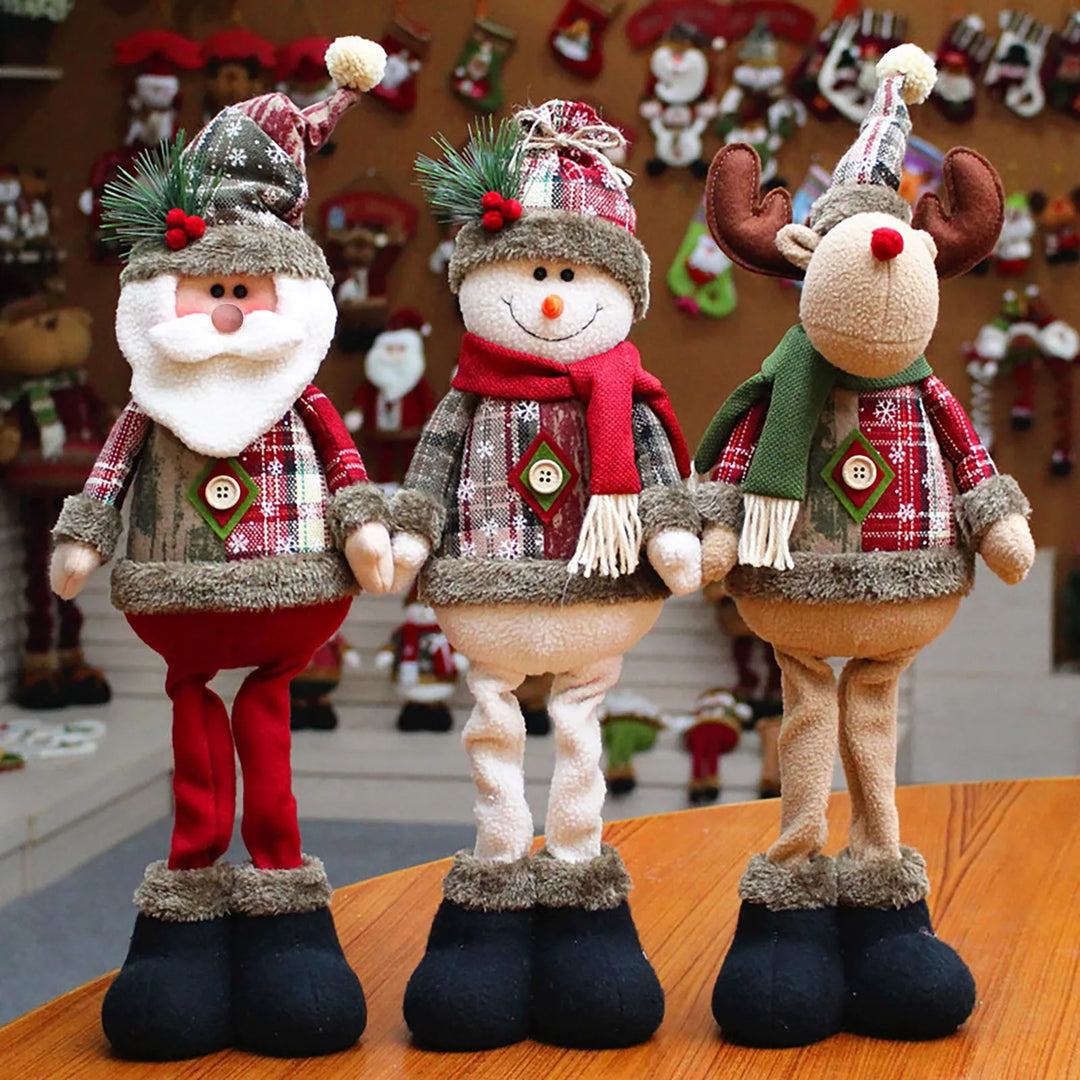 Three plush Christmas figurines including Santa Claus, snowman, and reindeer standing together on a wooden table.
