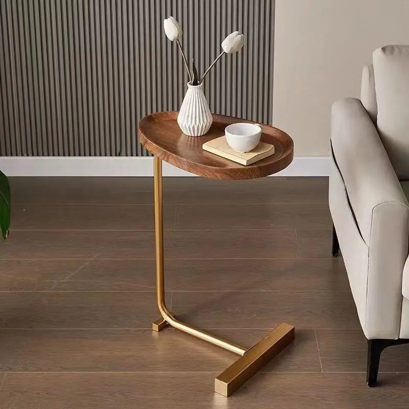 Nirethia C-shaped mobile side table with golden frame and wooden top placed next to a grey sofa