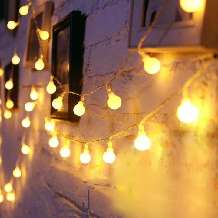 Close-up of illuminated white ball bulbs on a string light strand