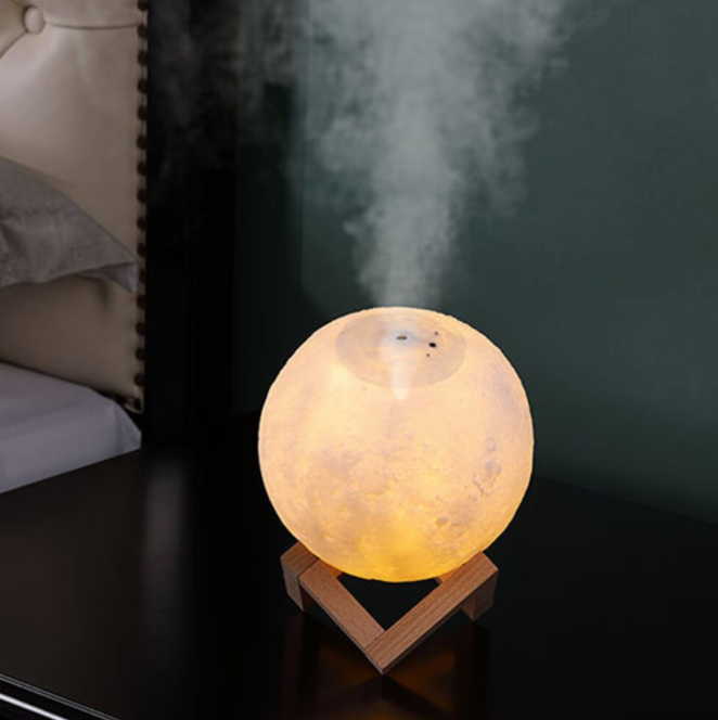 Glowing moon lamp humidifier releasing mist on a nightstand