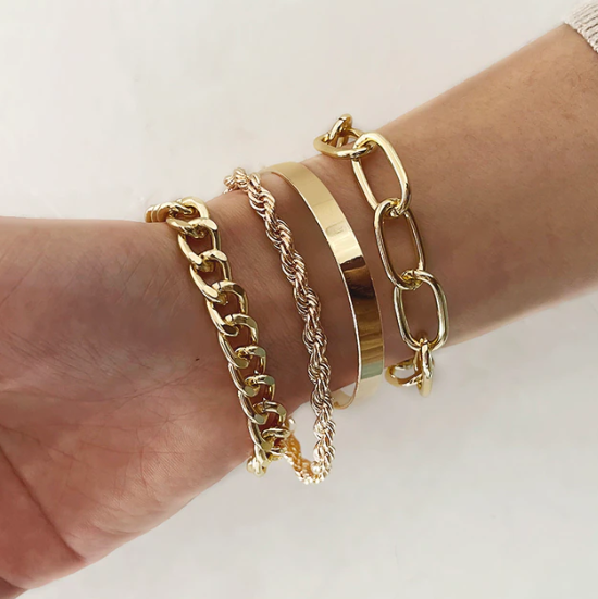 Close-up of four stacked metal bracelets showcasing interlocking designs