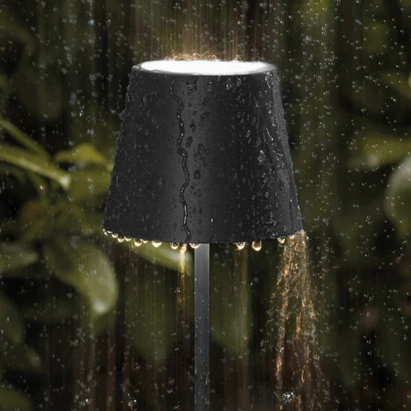 Water-resistant outdoor LED table lamp lighting a garden evening