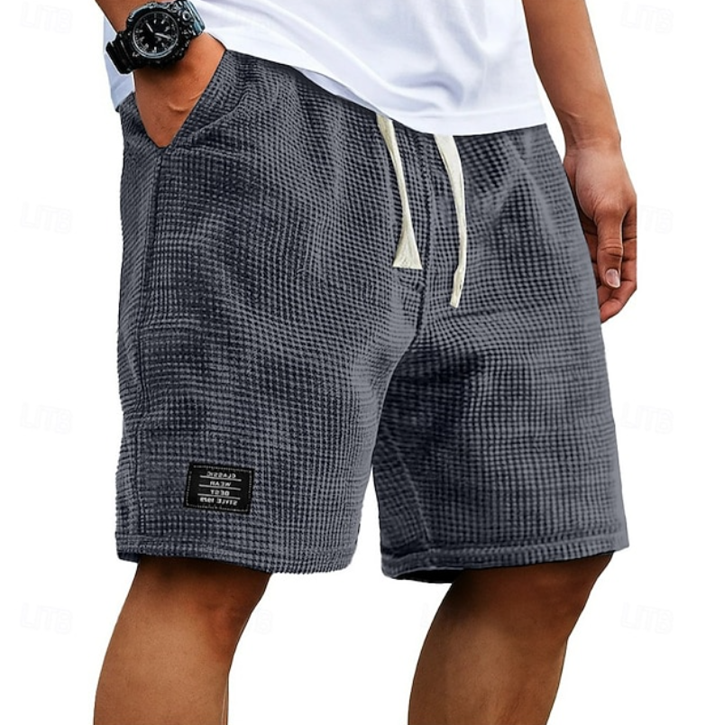 Close-up of a man wearing grey waffle-knit casual summer shorts with a drawstring