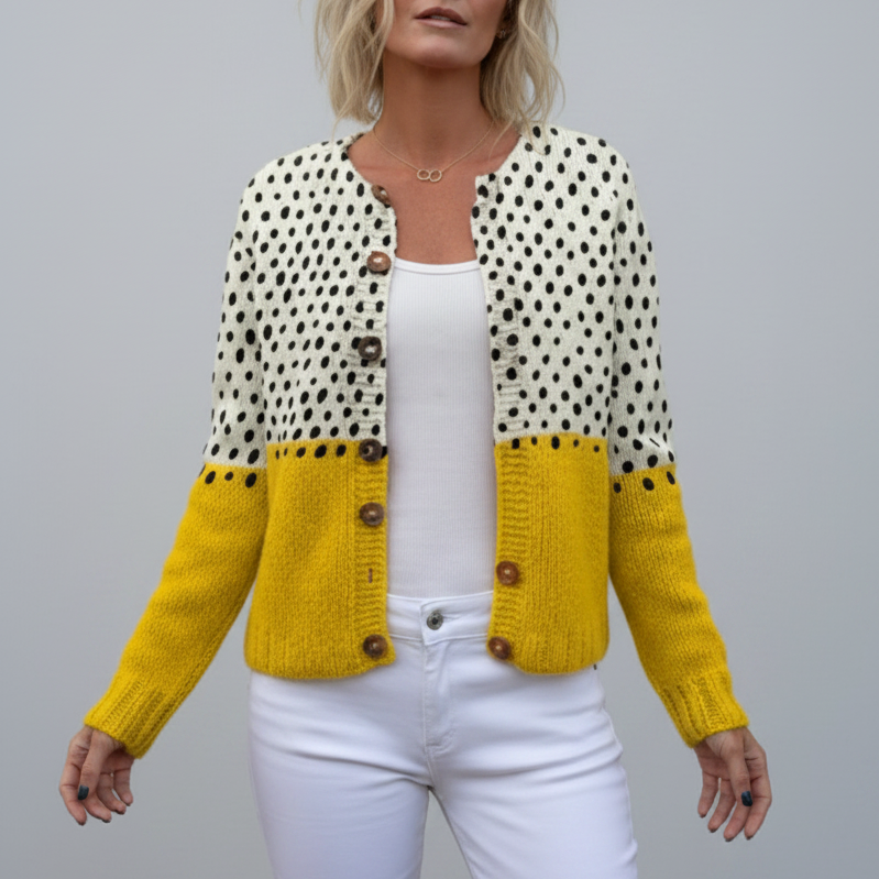 Woman wearing a yellow and white polka dot knitted cardigan against a grey background