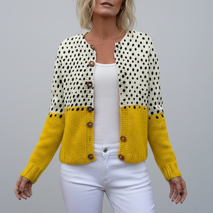Woman wearing a yellow and white polka dot knitted cardigan against a grey background