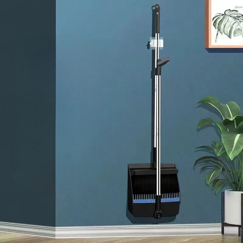 Black dustpan and broom set mounted on a blue wall for storage