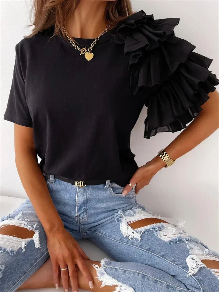 Close-up of a stylish black top featuring dramatic layered ruffle sleeves and a classic crew neckline.