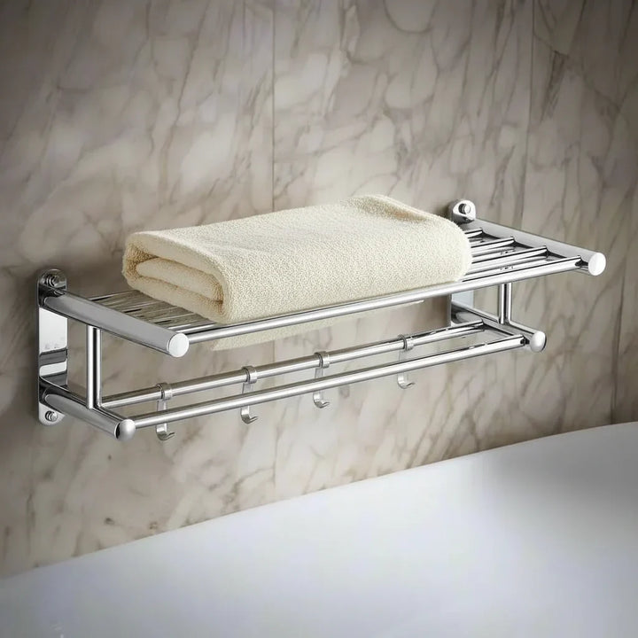 Stainless steel towel rack mounted on marble wall with folded beige towel on top shelf
