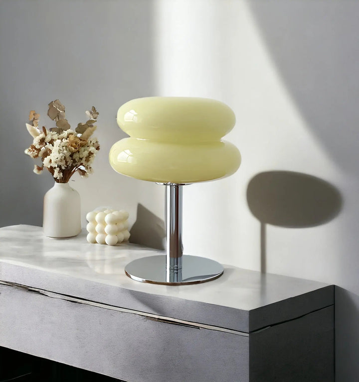 Cream colored macaron glass table lamp displayed on a sleek modern credenza