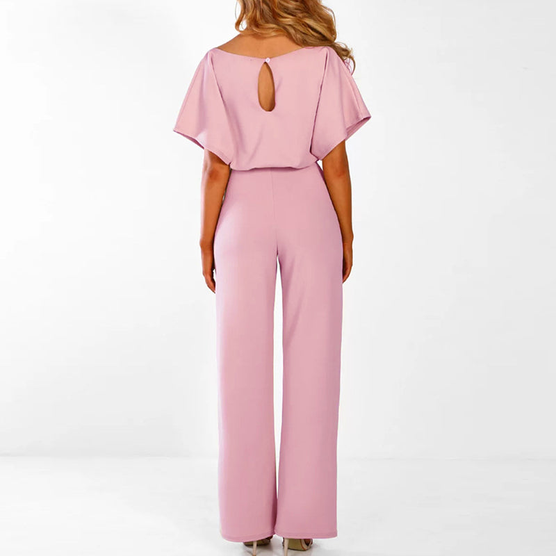 Back view of a woman wearing a pink short sleeve belted wide leg jumpsuit