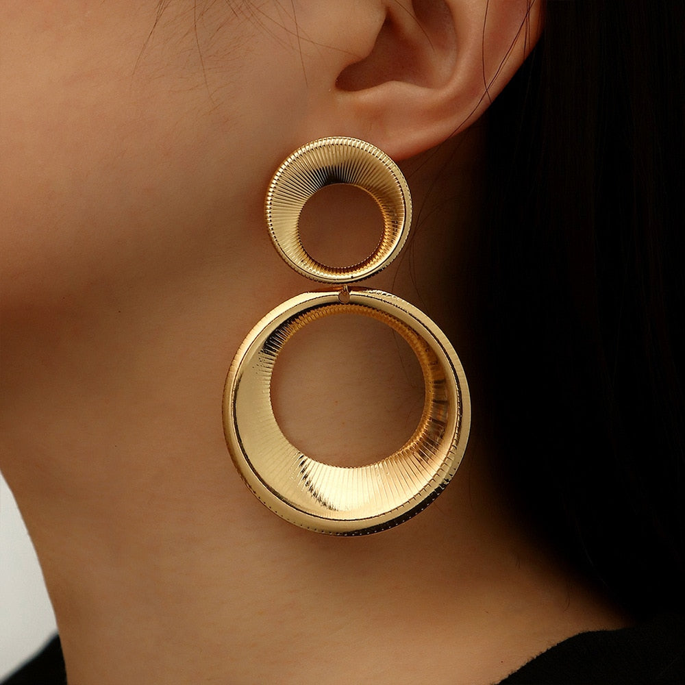 Model wearing gold double circle statement earrings with ribbed 3D texture