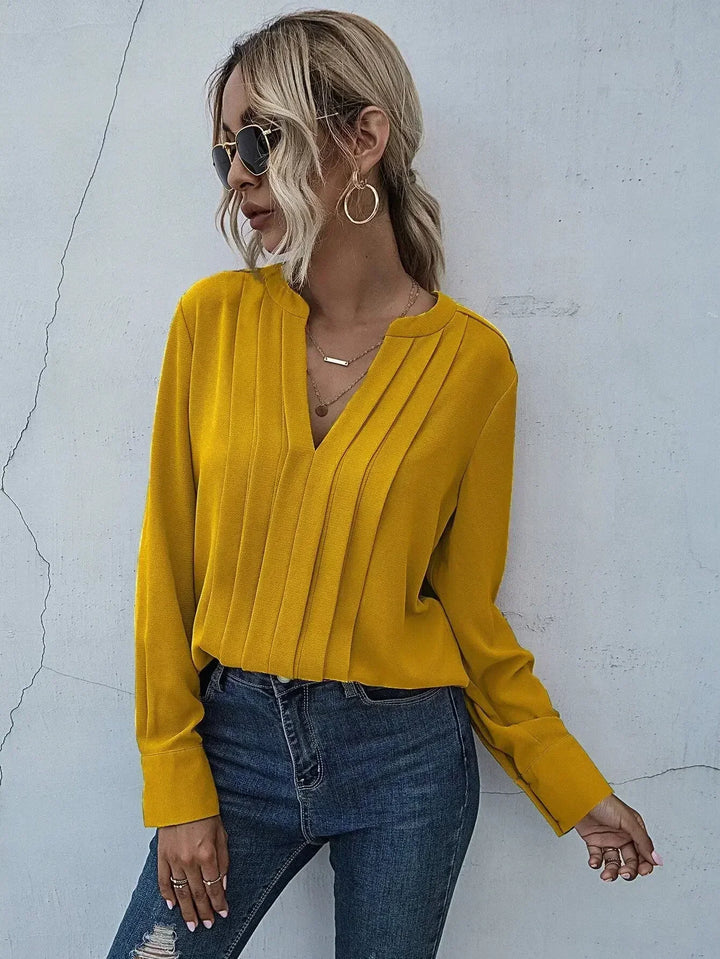 Model wearing bright yellow pleated blouse with long sleeves