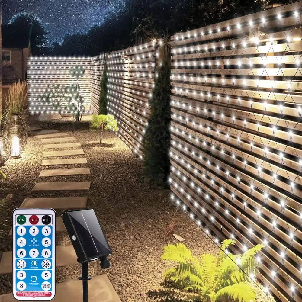 Solar fairy light net installed along a wooden garden fence at night