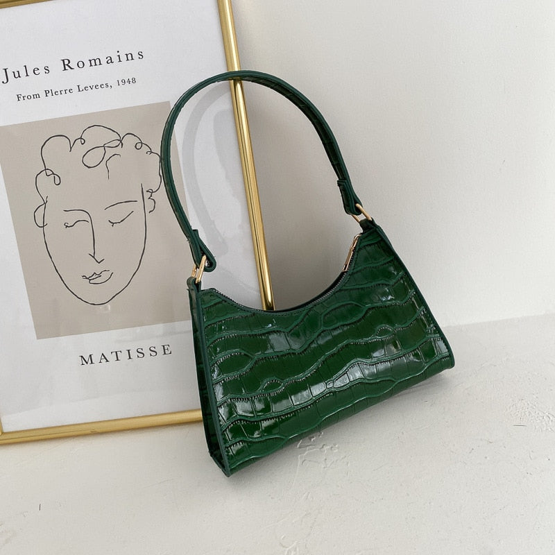 Deep green textured women's shoulder purse resting near artwork
