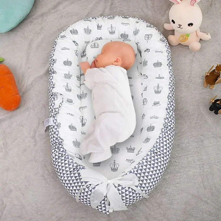 Baby sleeping peacefully inside a portable gray patterned baby bassinet nest