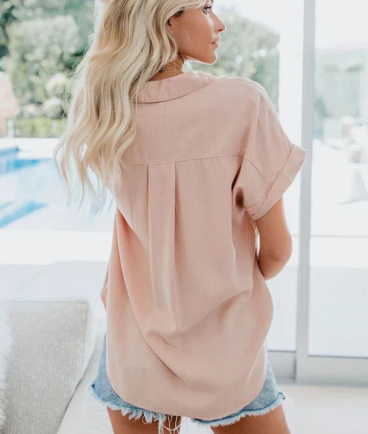 Flat lay styling of women's casual top with accessories and trousers
