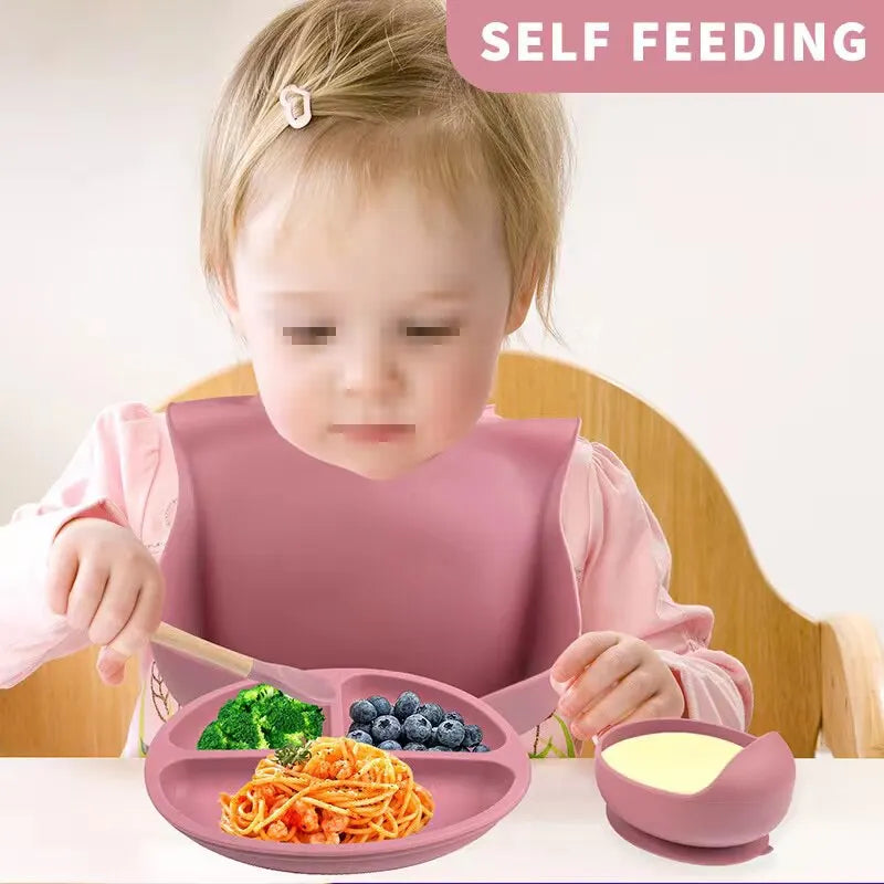 Baby eating with a pink silicone divided plate and suction bowl