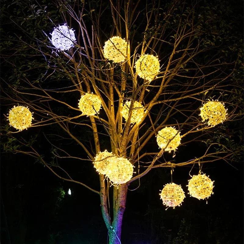 Illuminated Sphere rattan globes hanging on branches during evening time