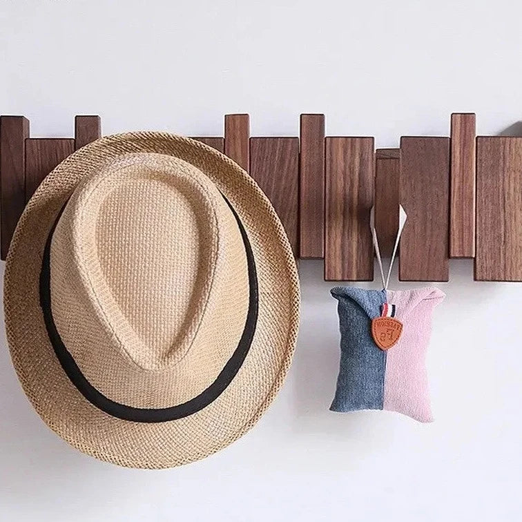 Wooden wall rack holding a straw hat and a small pouch
