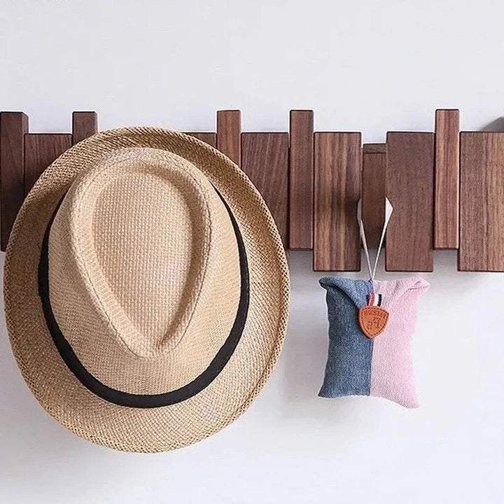 Wooden wall rack holding a straw hat and a small pouch