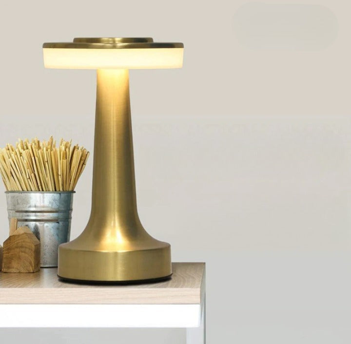Close-up view of the gold cordless table lamp illuminating a tabletop next to a container of wooden sticks