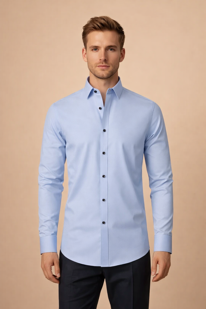Man wearing a light blue long-sleeve button-down shirt with a structured collar in a studio setting.