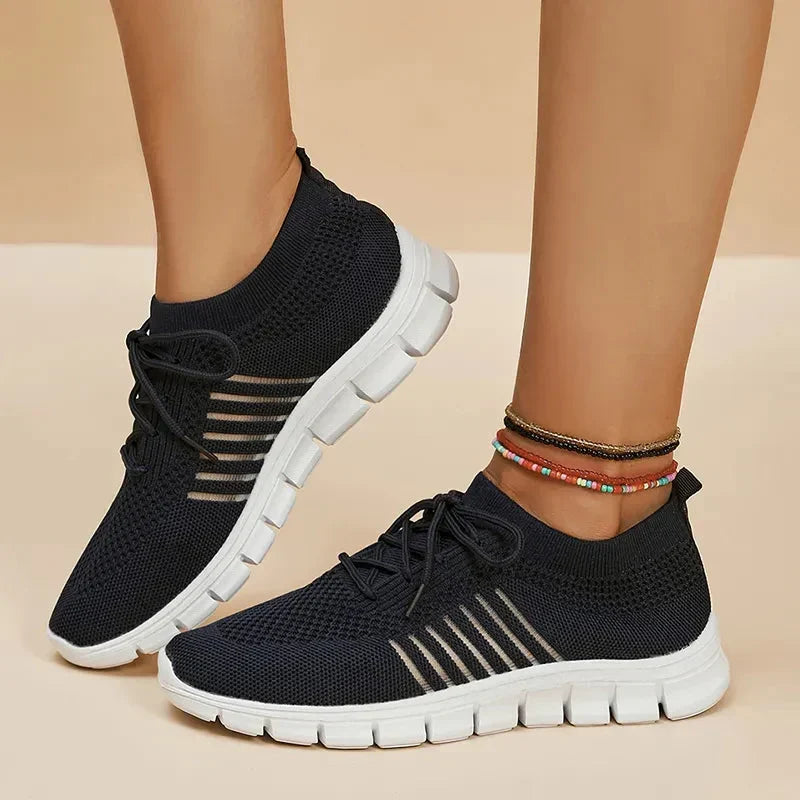 Black women's orthopedic walking sneakers with white soles worn outdoors