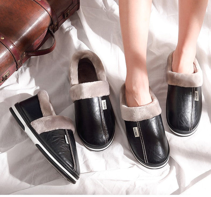 Unisex black warm indoor slippers displayed with feet on white fabric background