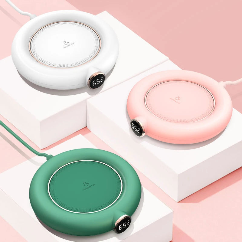 White, pink, and green smart digital mug warmers displayed on white blocks